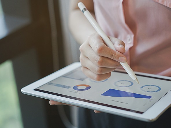 woman using tablet with stylus to look at graphs and charts